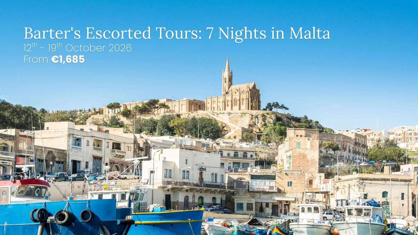 Harbor town in Malta with blue boats and a hilltop church under a clear sky