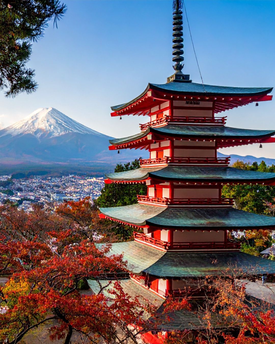 Five-story pagoda with red autumn leaves, overlooking Mount Fuji under a clear blue sky