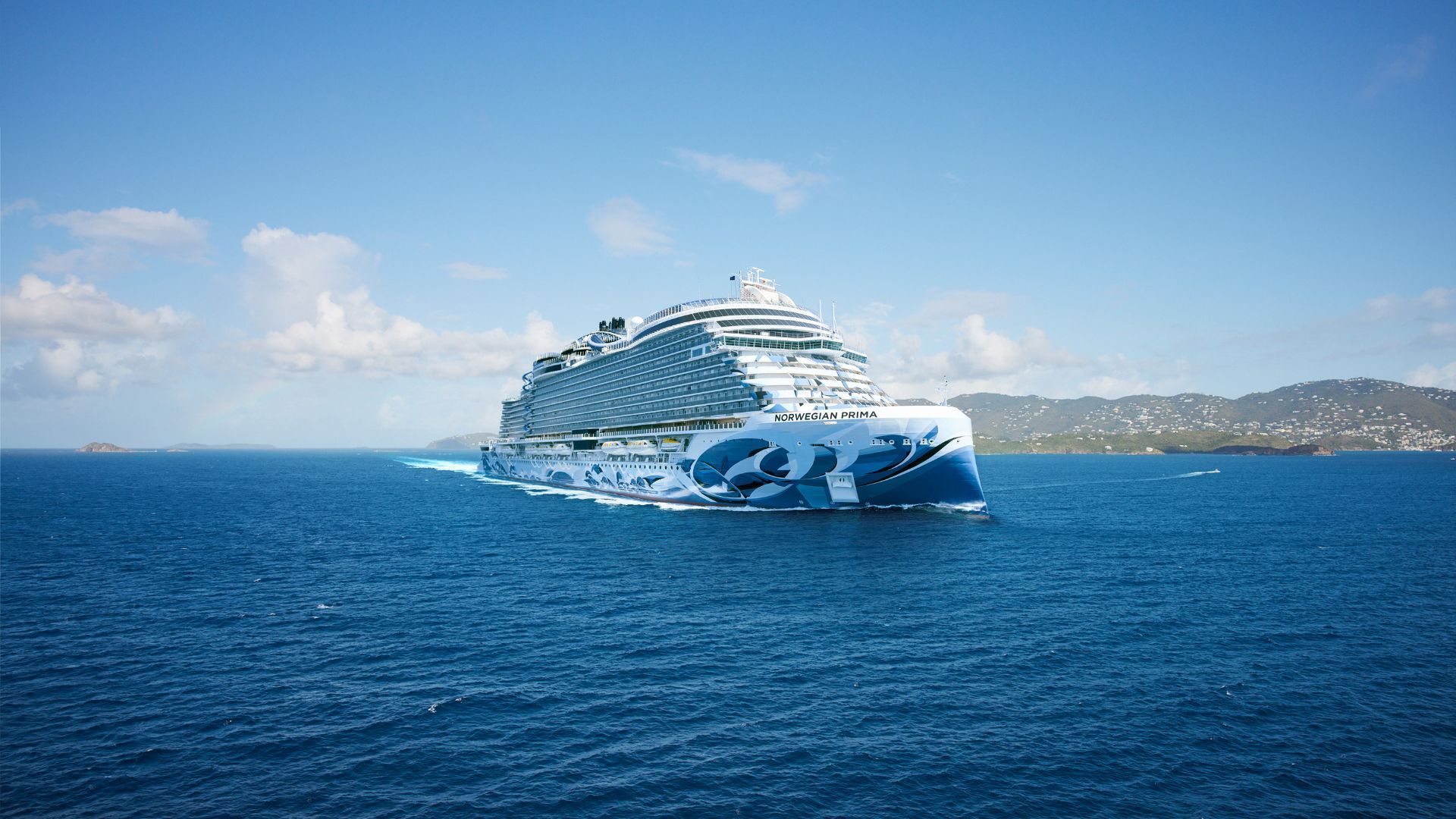 A large cruise ship Norwegian Prima with blue and white design sails on a sunny ocean.