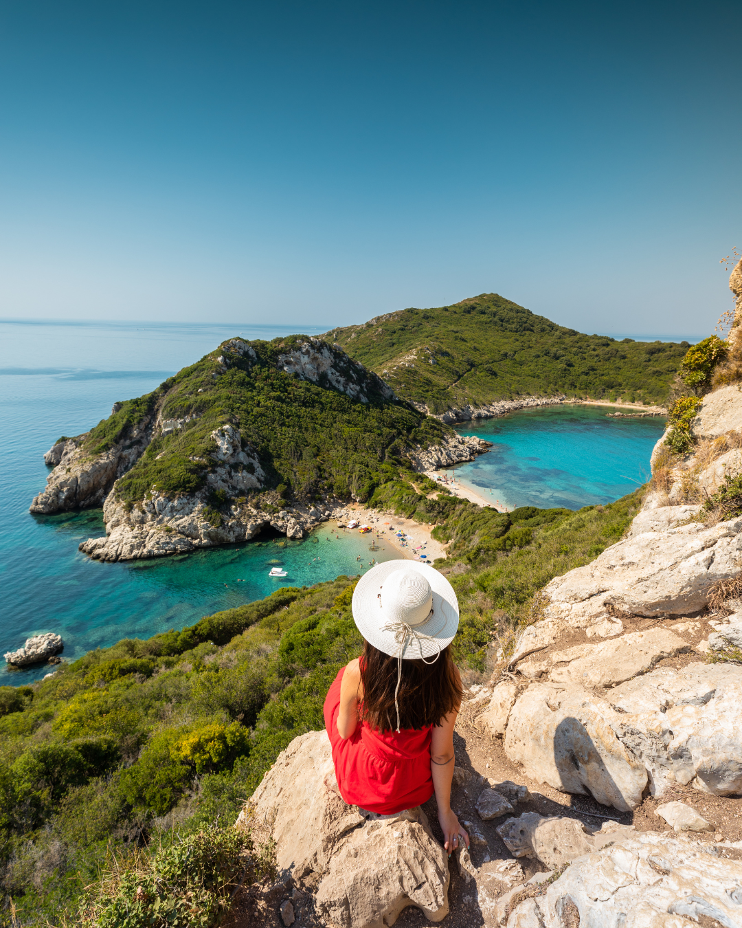 Woman Sitting on a Rock Looking to Porto Timoni Beach in Corfu, Afionas - Greece Holidays Barter's Travelnet