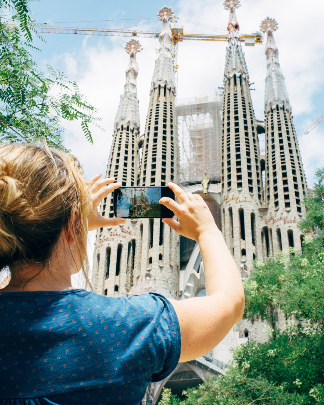Woman Taking a Photo on a Smartphone to the Sagrada Familia Basilica in Barcelona, Spain - Barcelona Holidays Barter's Travelnet