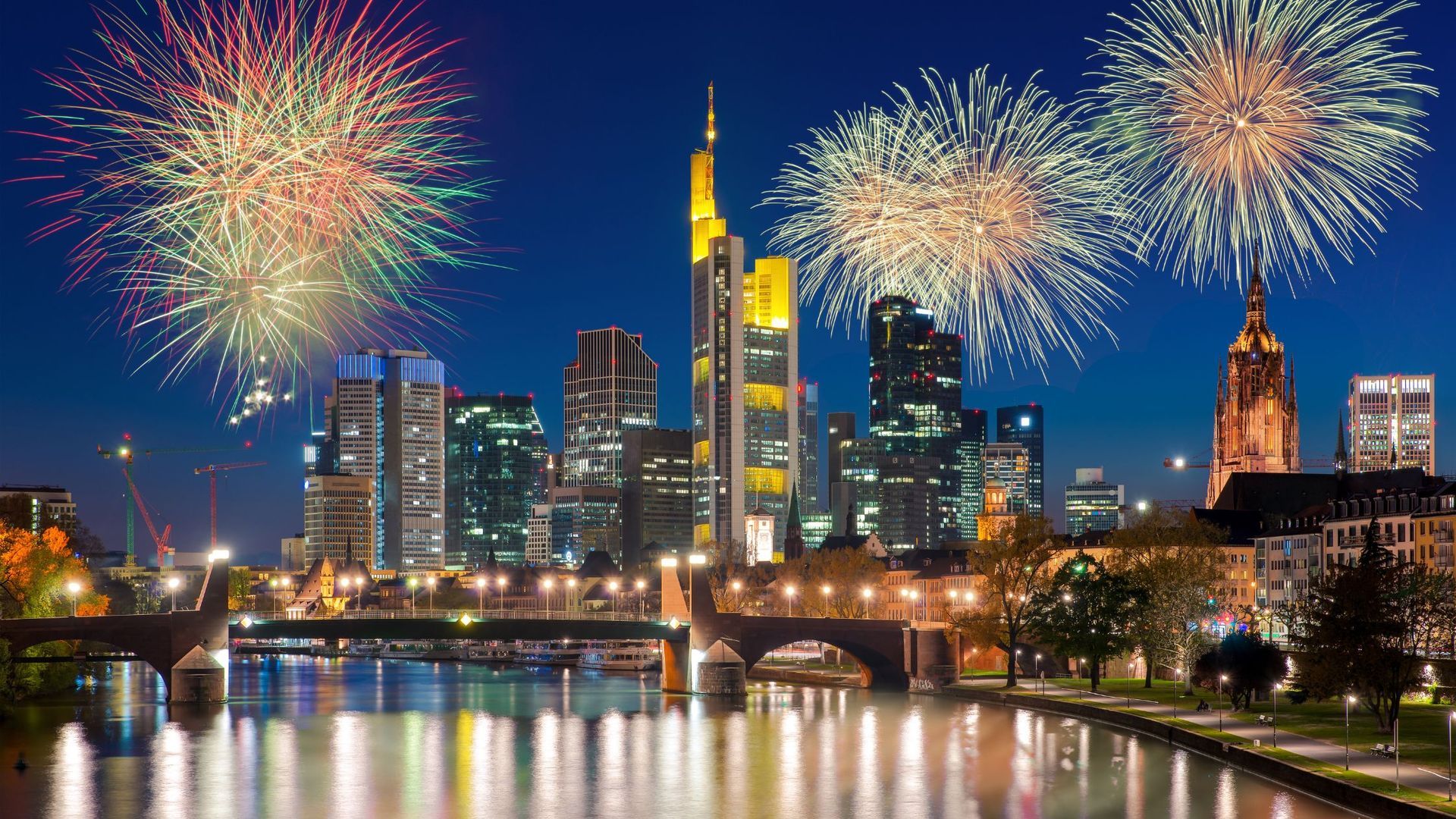 Fireworks are exploding over a city skyline at night.