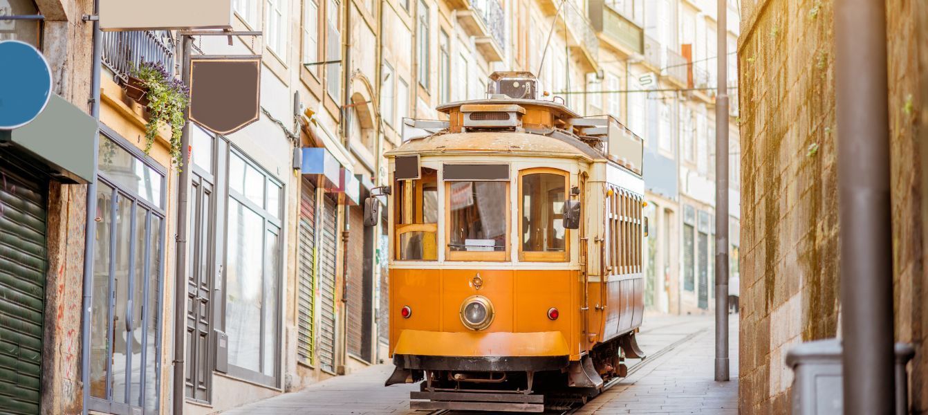 A yellow trolley is driving down a narrow street.