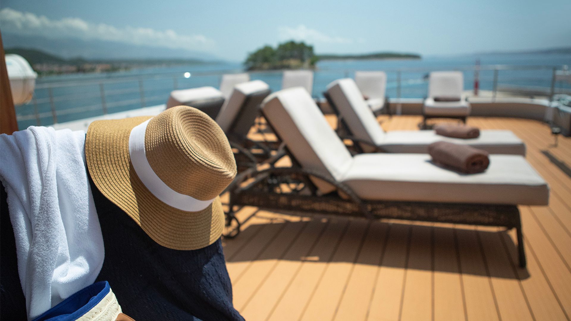 A hat and towel are hanging on a wooden deck overlooking the ocean.