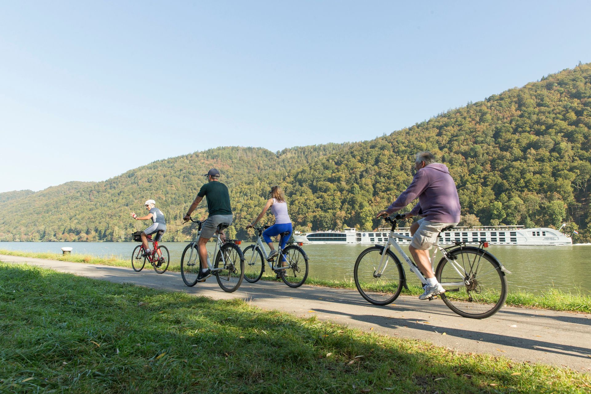 A group of people are riding bicycles on a path next to a body of water.