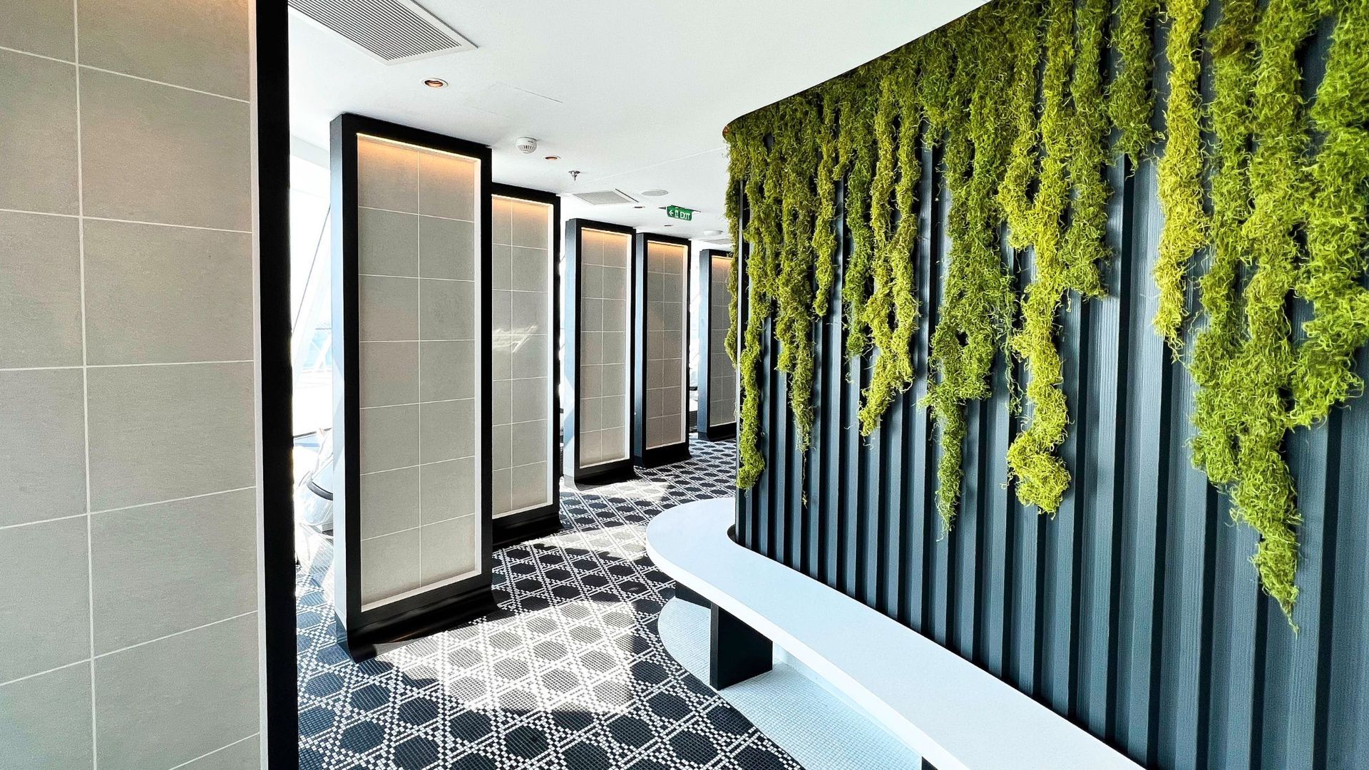 A hallway with a green wall and a bench sauna