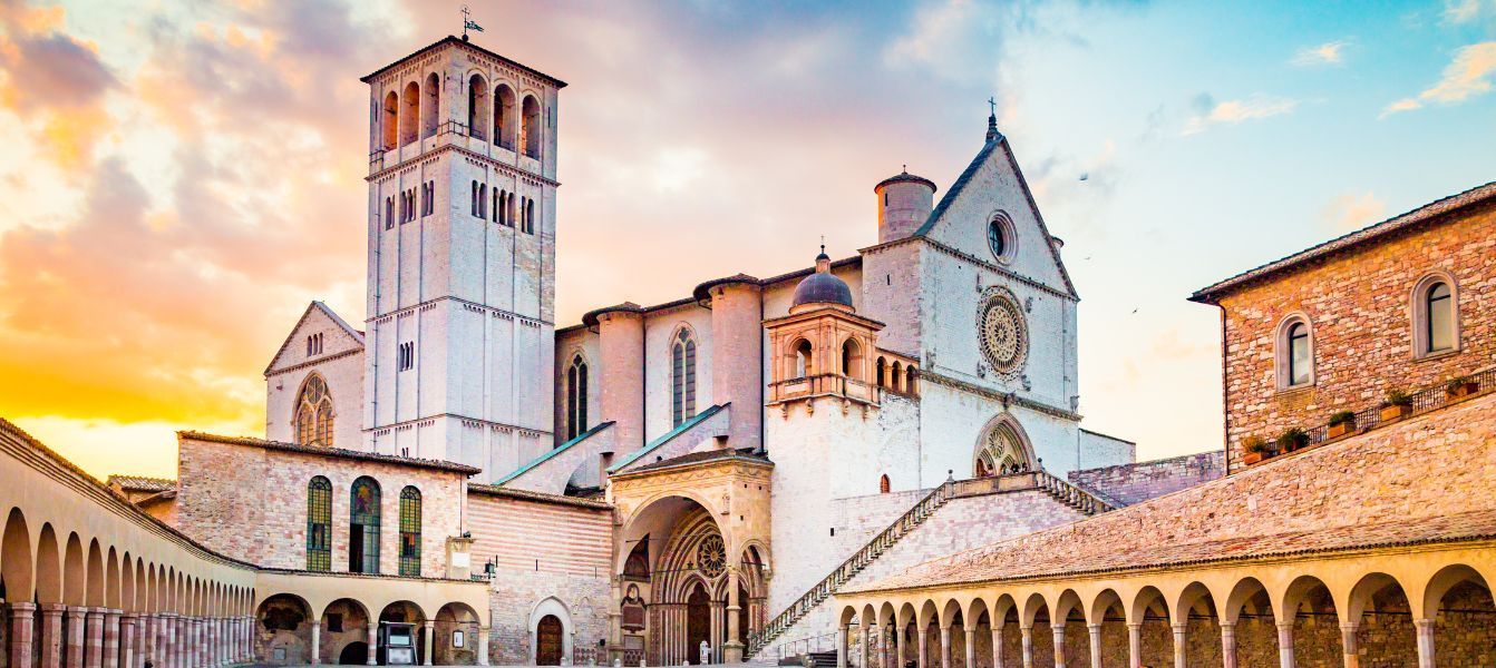 A large white building in Assisi with a clock tower on top of it.