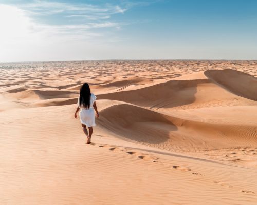 girl walking through desert in dubai