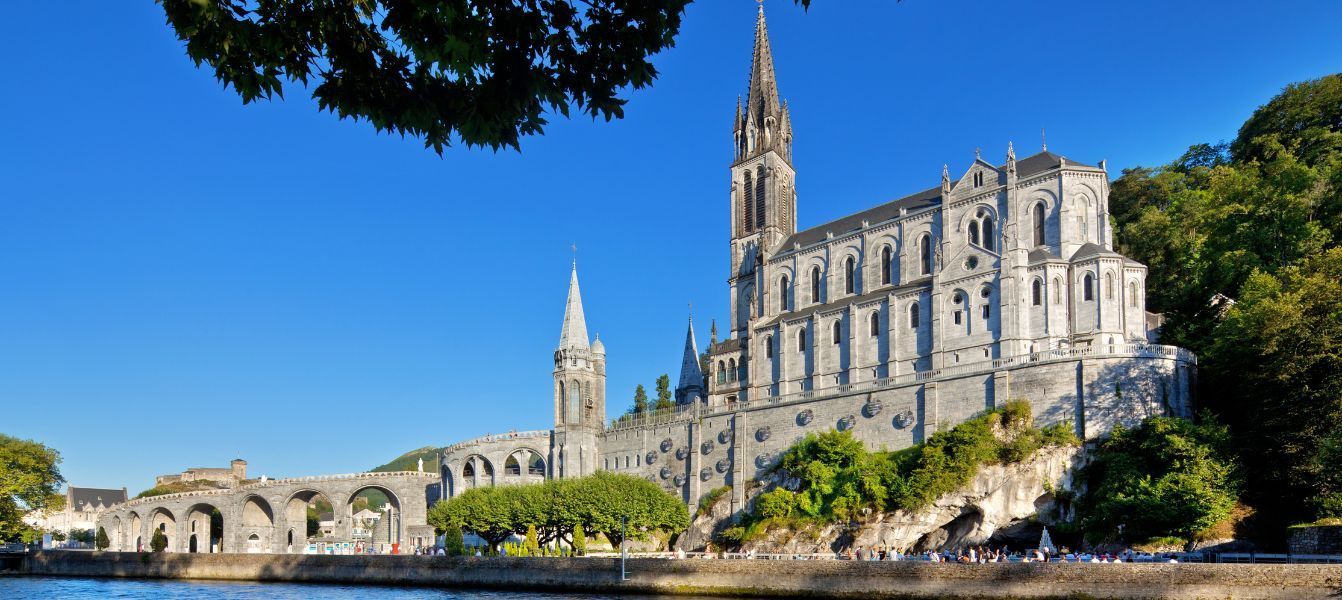 A large church sitting on top of a hill next to a body of water.