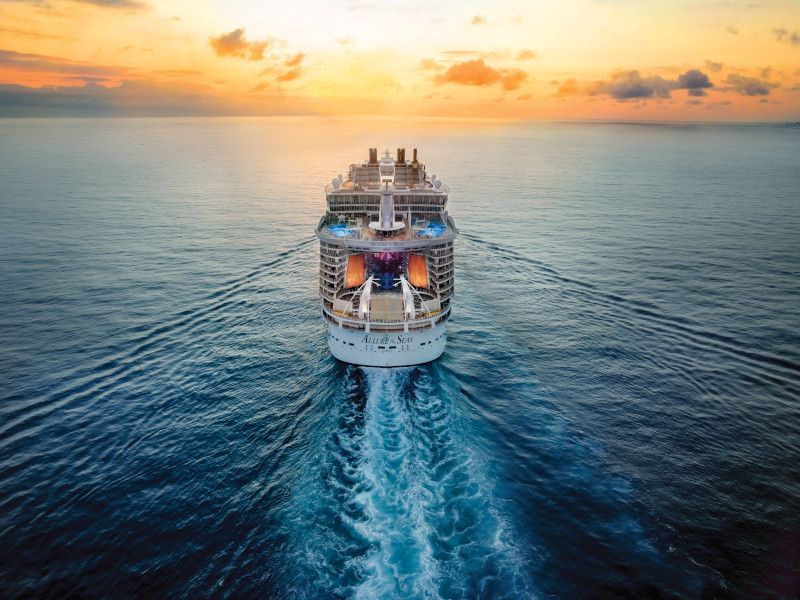 an aerial view of a cruise ship sailing in the ocean at sunset .