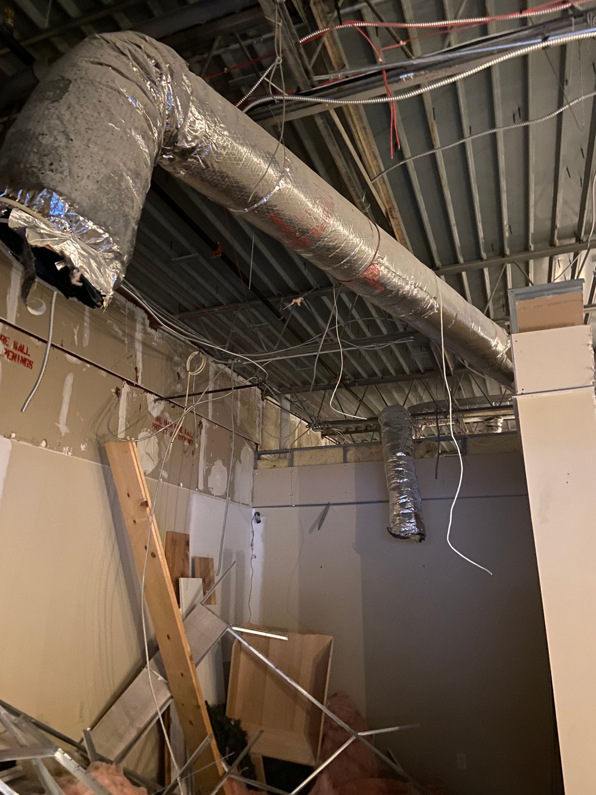 HVAC ductwork in a construction zone, with exposed wiring and unfinished walls.