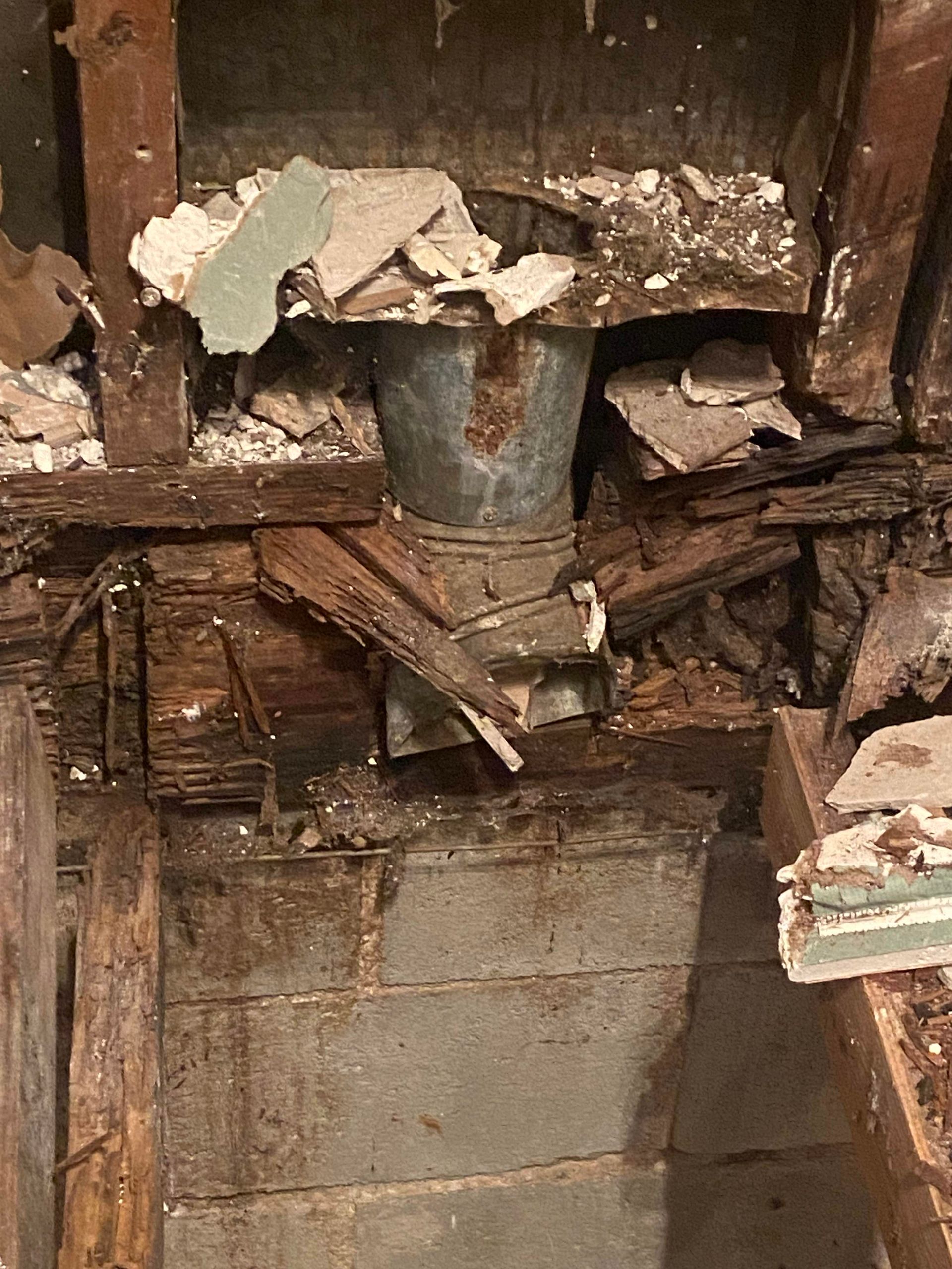 A close-up of a decaying wood and cement structure, possibly an old chimney or a foundation.