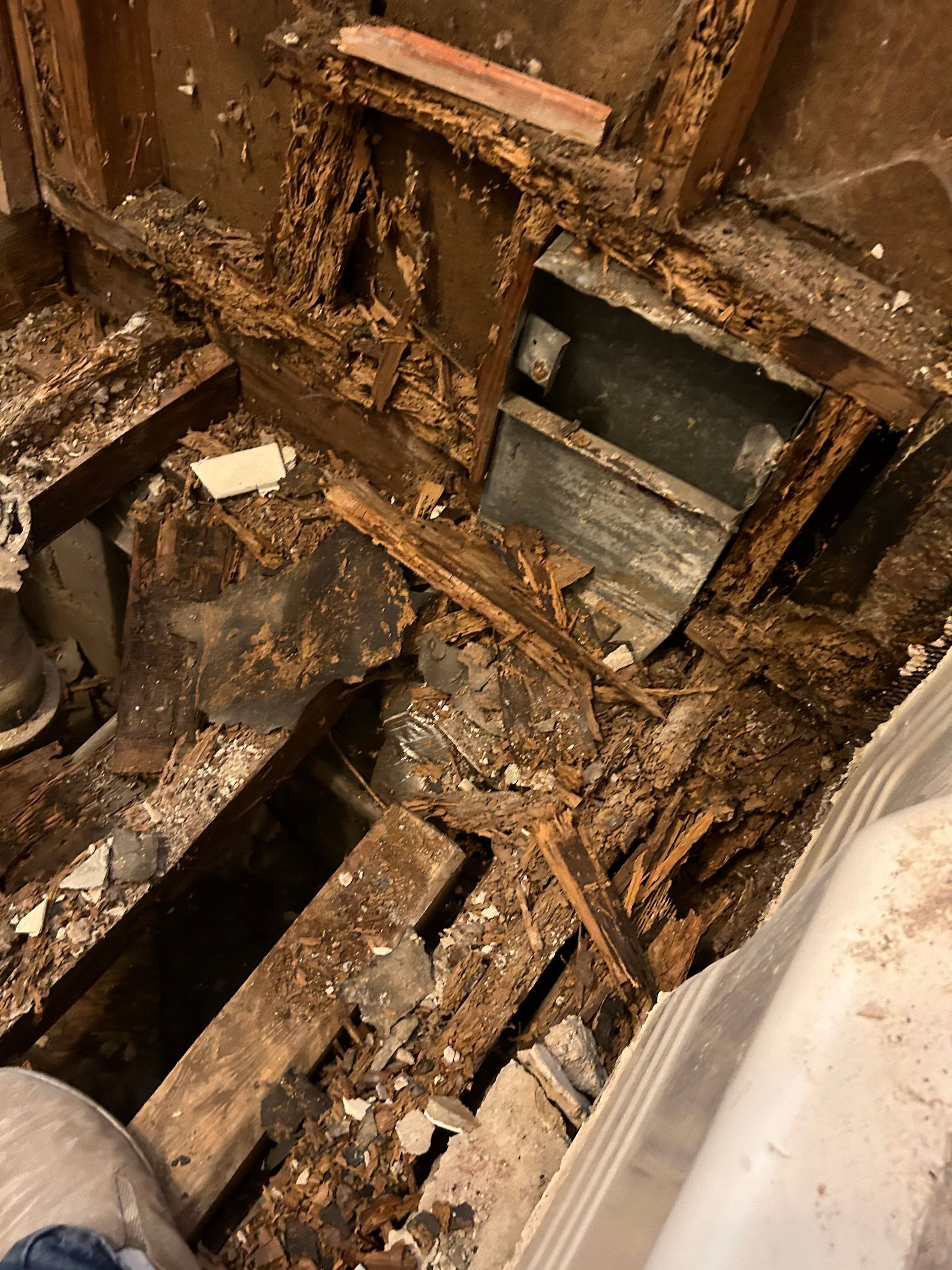 Severe wood rot damage in a bathroom, revealing rotted framing and subfloor.