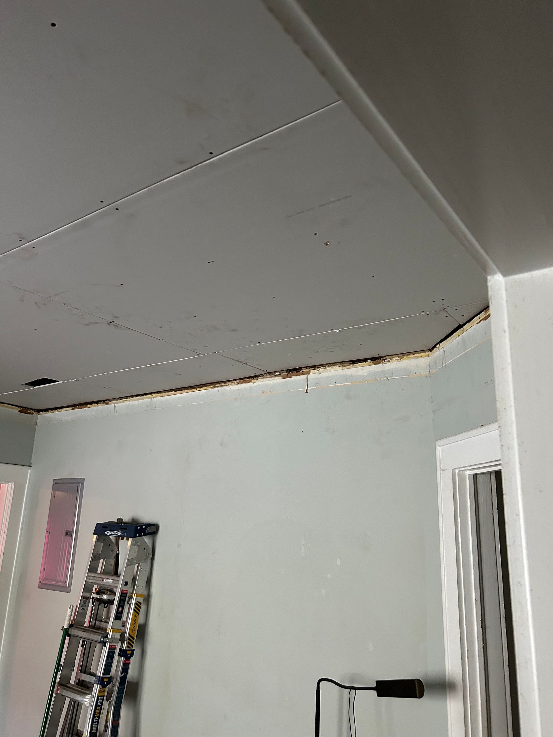 Ceiling with exposed wood and drywall. Light blue walls, ladder and doorway.