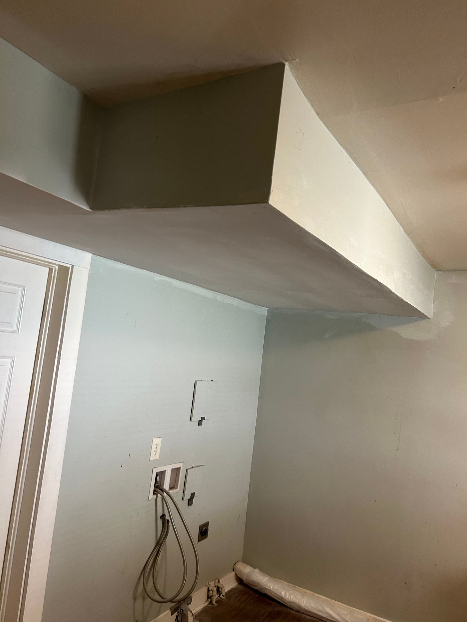 A white rectangular ceiling beam extends across a light blue-painted room. Electrical wires hang below.