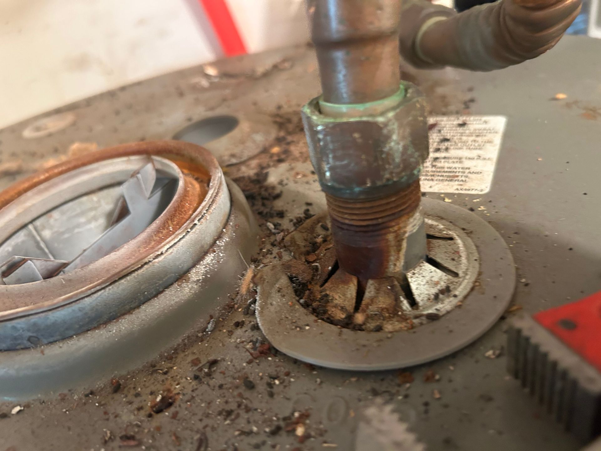 Close-up of corroded water heater fittings and insulation damage.