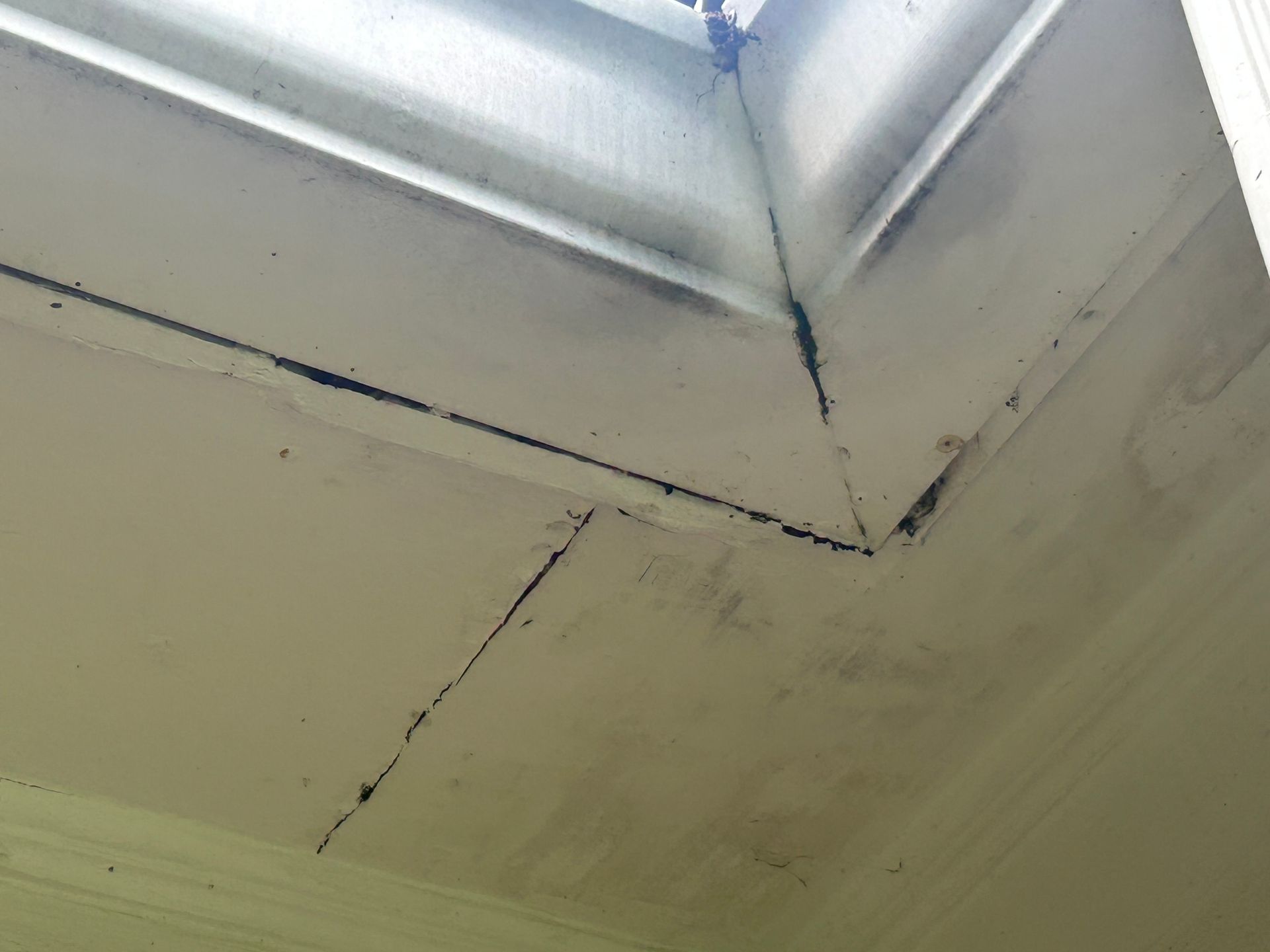 White painted soffit with dark staining at the seams.