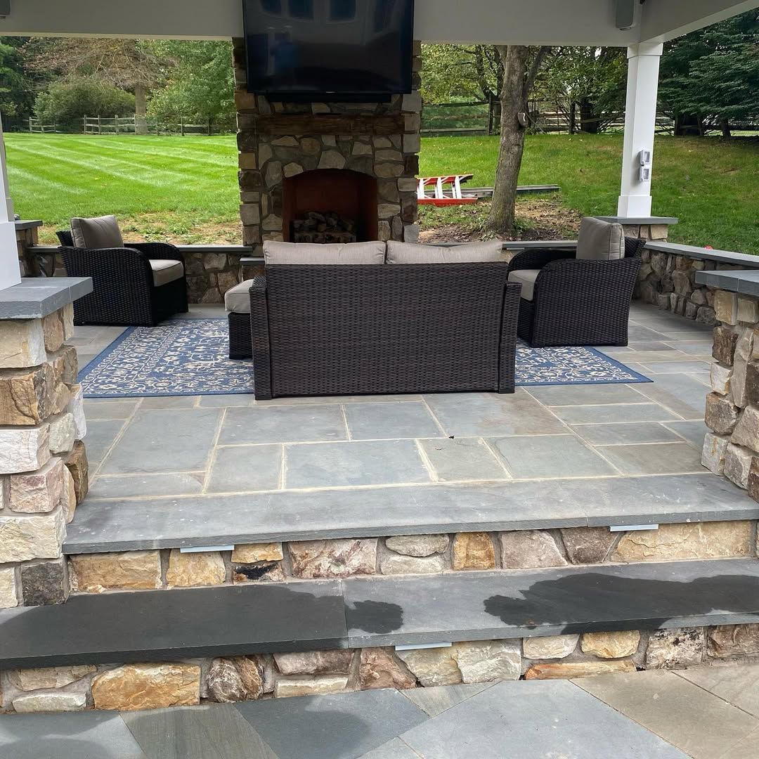 A patio with wicker furniture and a stone fireplace