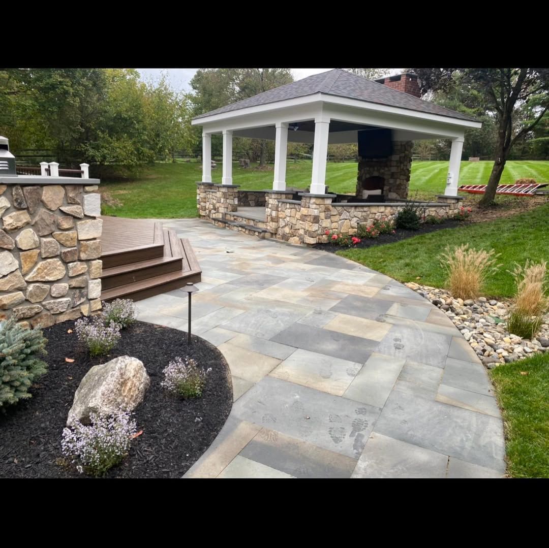 A patio with a gazebo and a fireplace in the backyard.