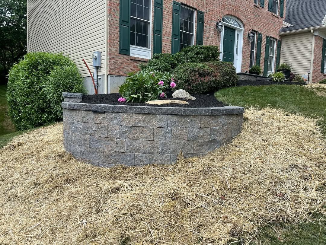 A brick wall with flowers and rocks in front of a house.