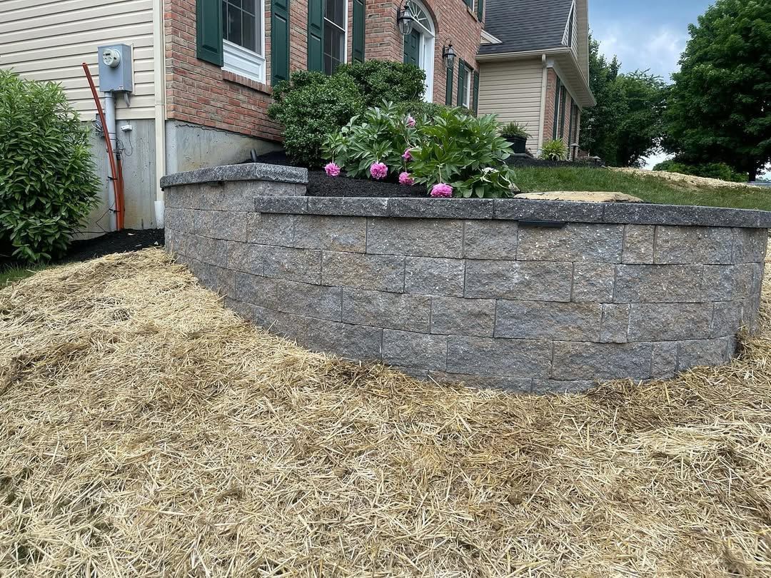 A brick wall with flowers in it in front of a house.