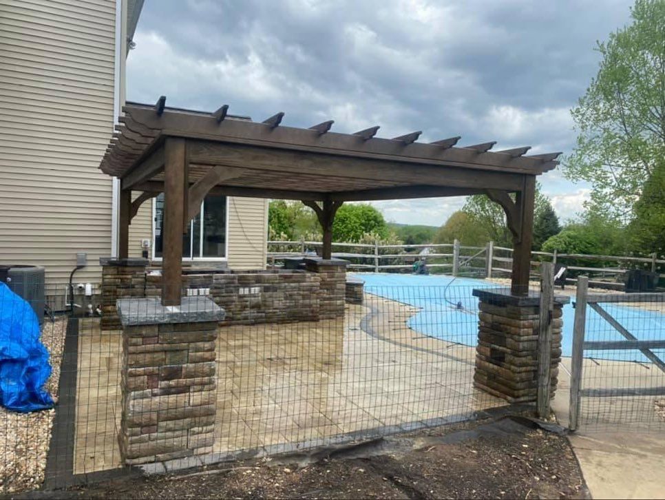 A wooden pergola is sitting next to a swimming pool.