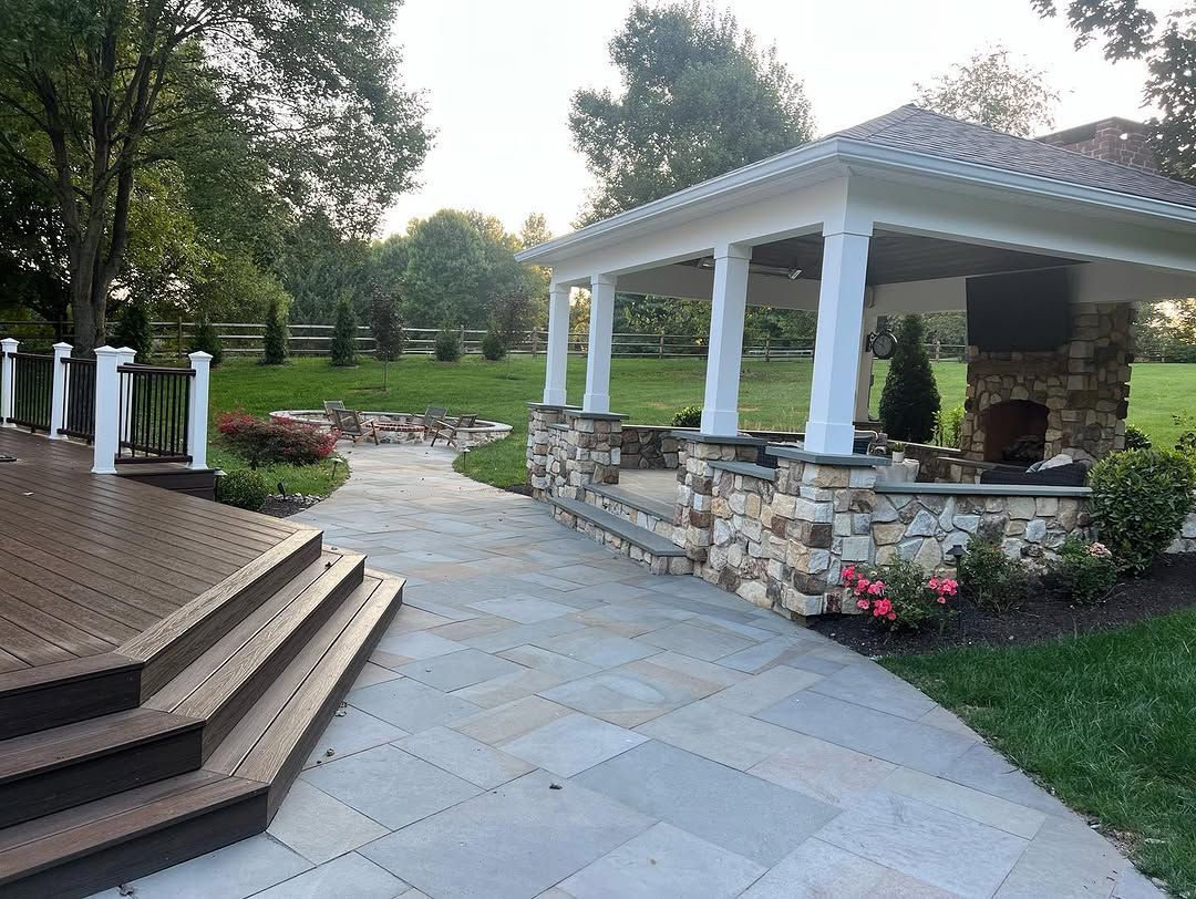 A patio with a gazebo and a fireplace in the backyard.