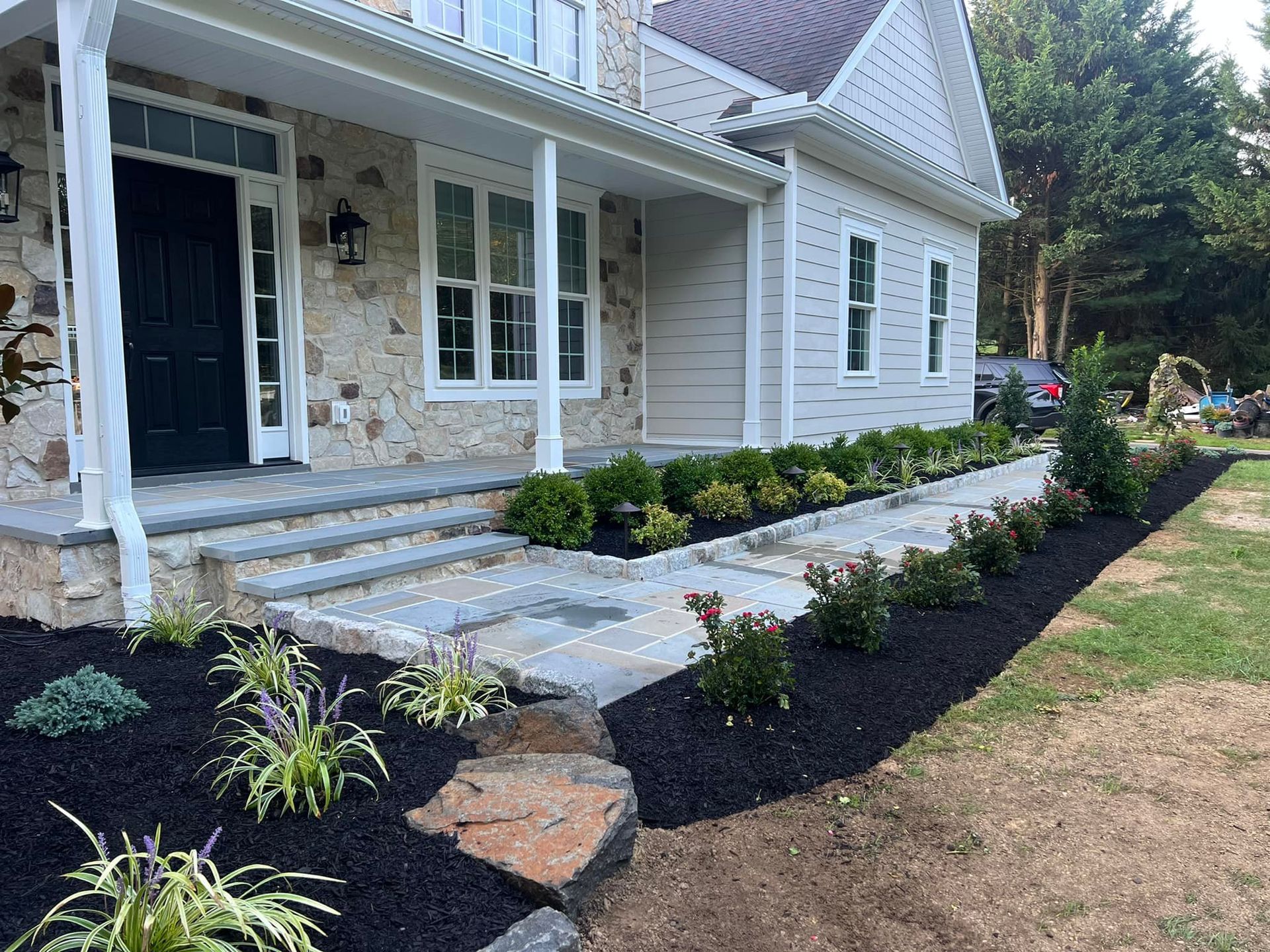 A large white house with a black door and a stone walkway leading to the front door.