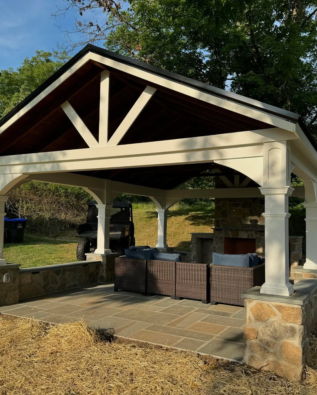 A white gazebo with a wooden roof is sitting in the middle of a yard.