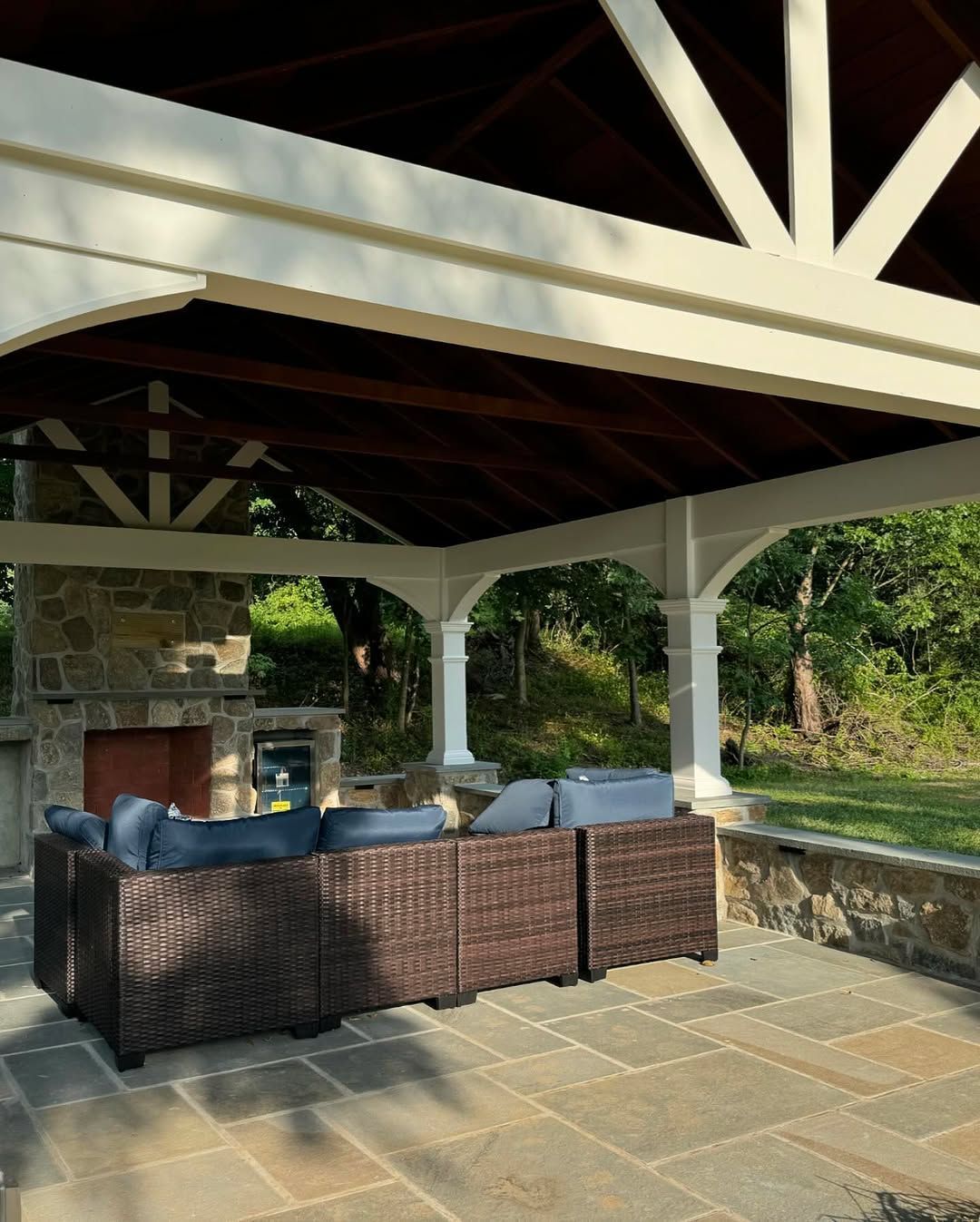 A patio with wicker furniture and a fireplace under a canopy