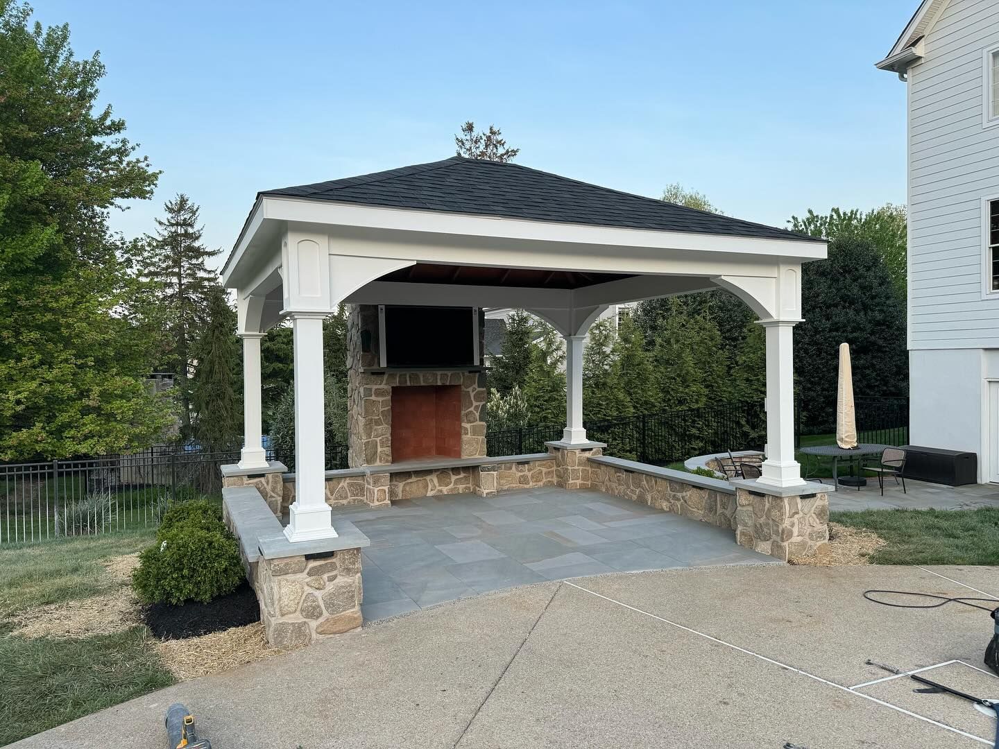 A gazebo with a fireplace and television underneath it