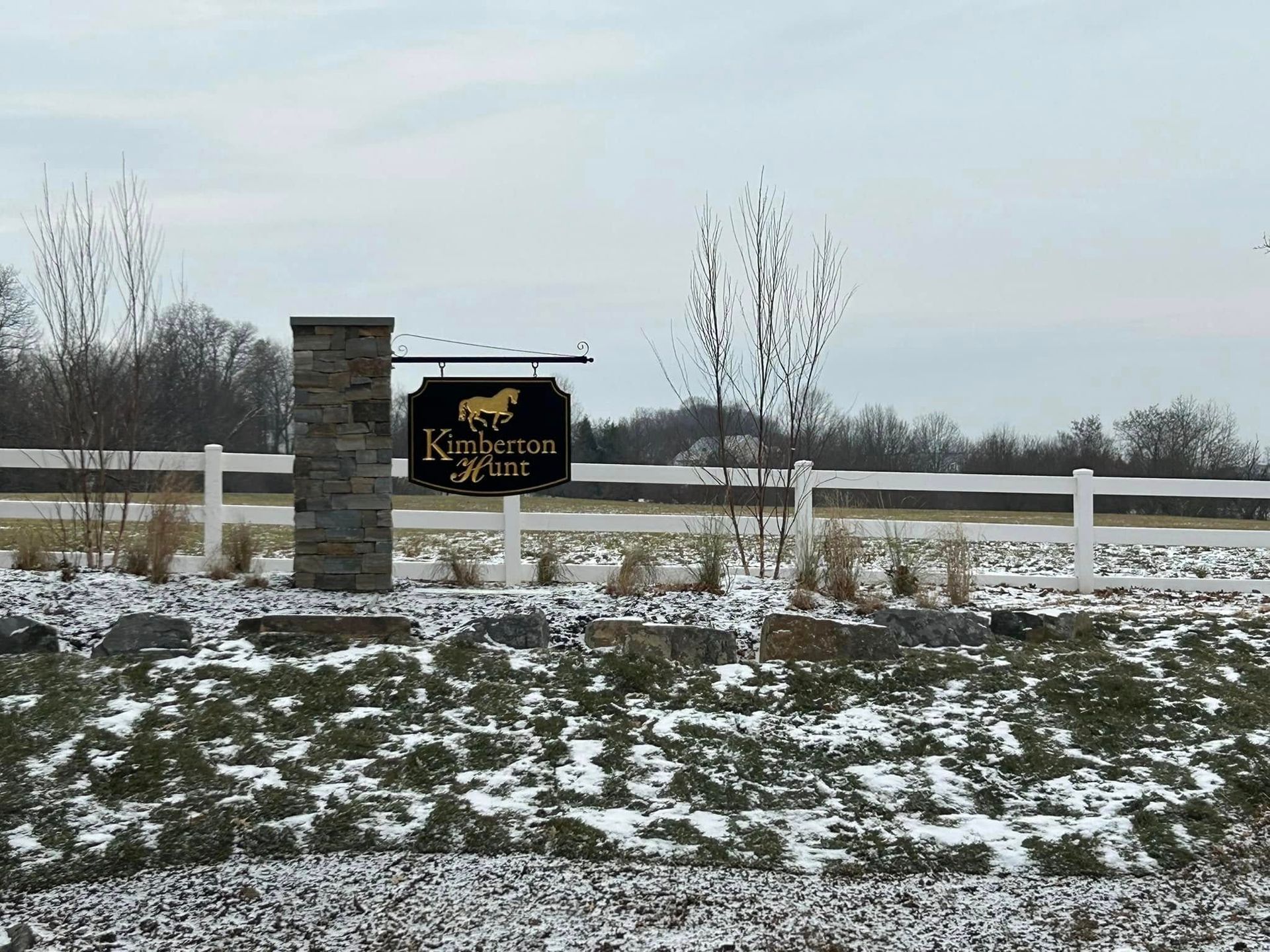 A sign with a horse on it is in the middle of a snowy field.