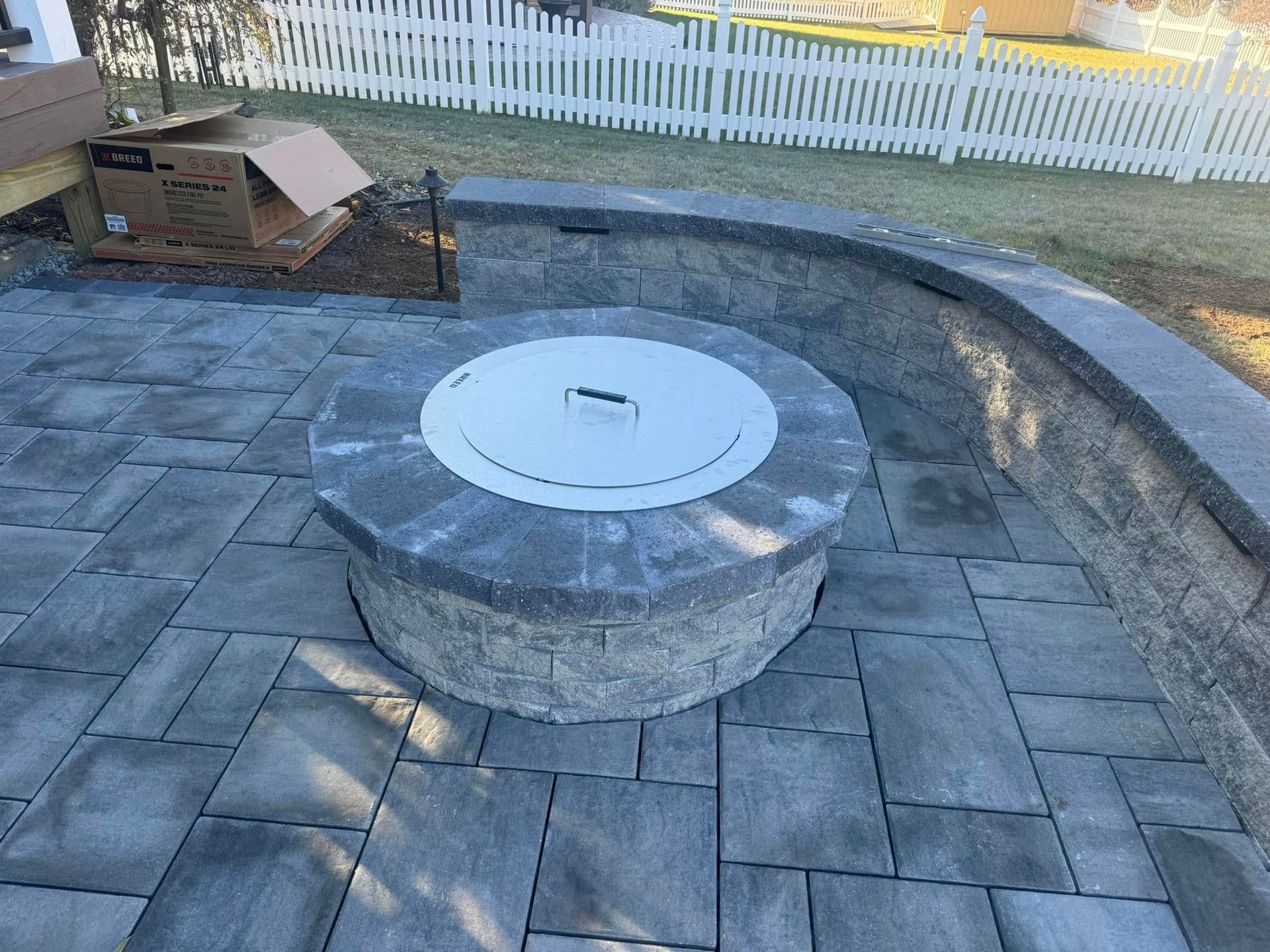 A fire pit is sitting on top of a brick patio.