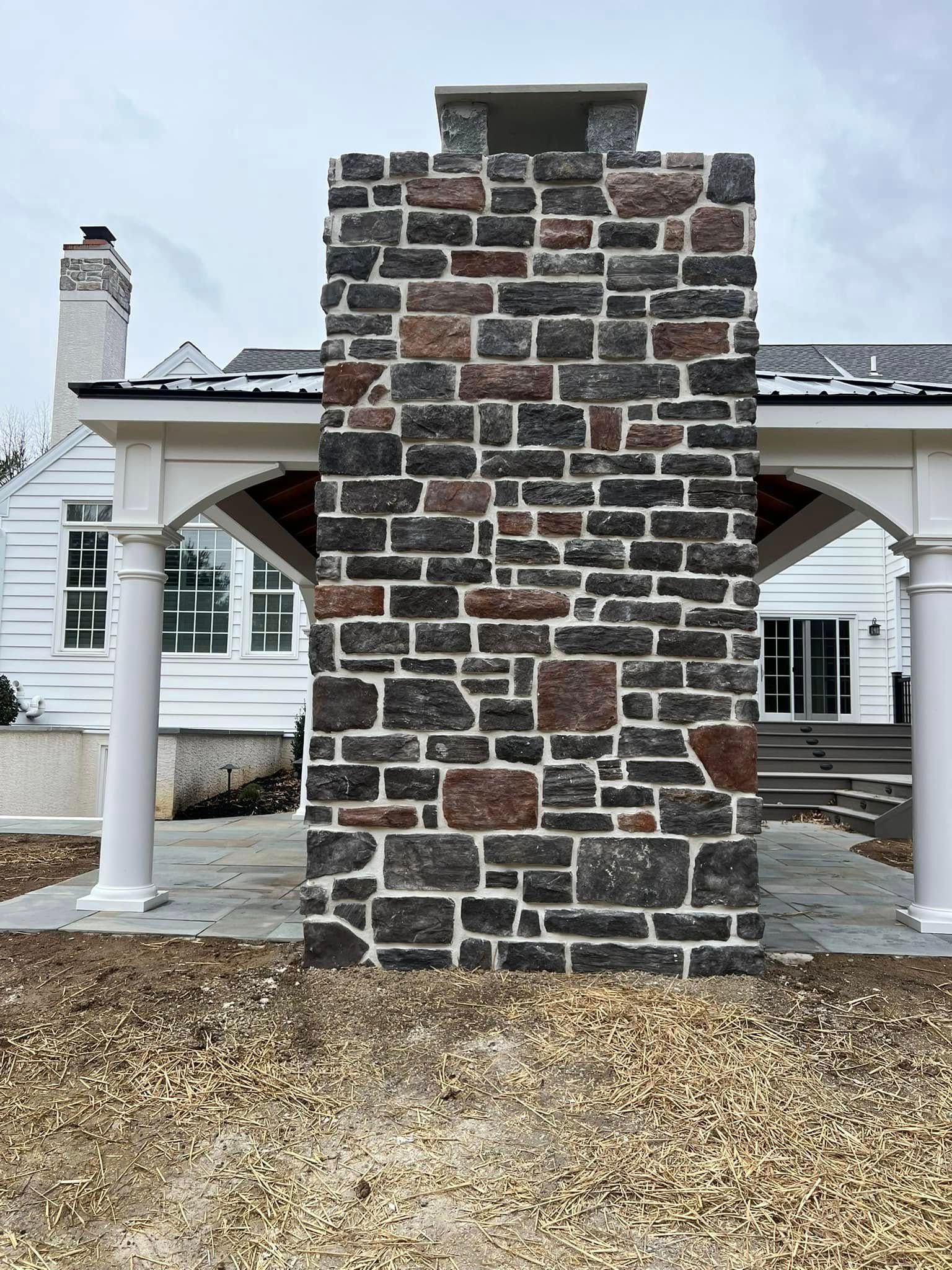 A large brick chimney is sitting in front of a house.