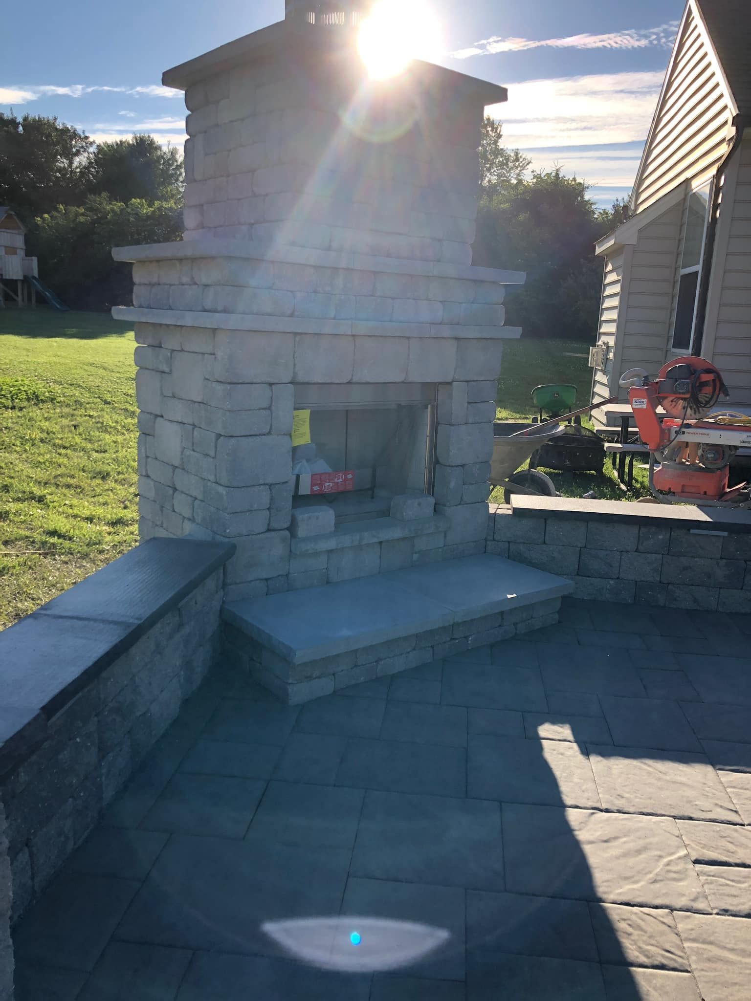 A stone fireplace is sitting on a patio next to a house.