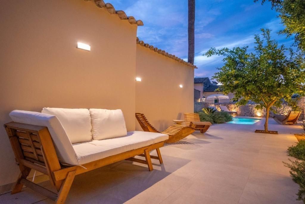 Patio exterior con sofá blanco, tumbonas y una pequeña piscina, iluminada al anochecer.