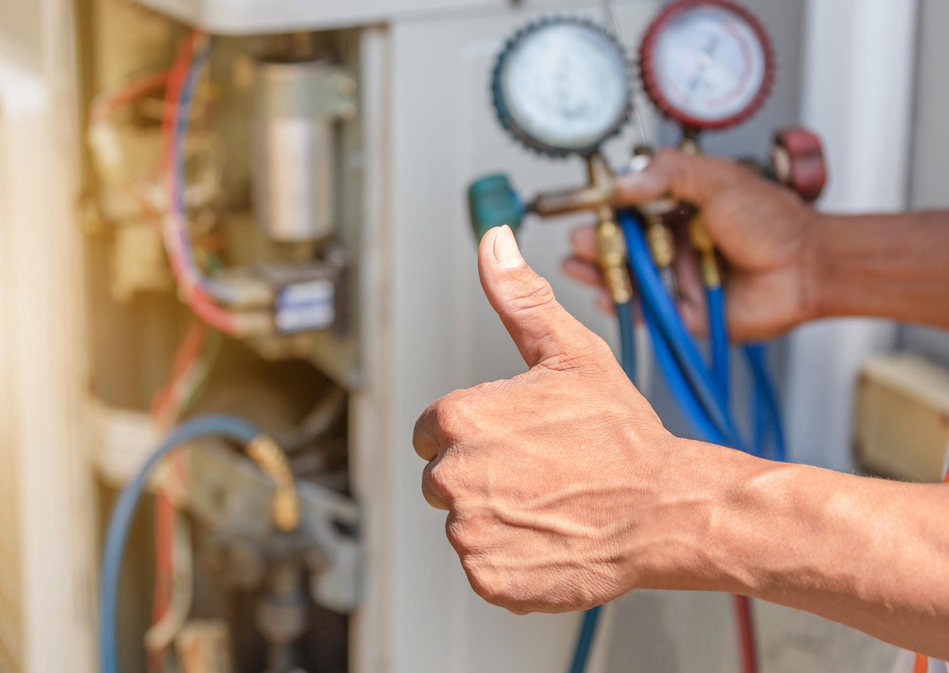 A man is giving a thumbs up while working on an air conditioner.