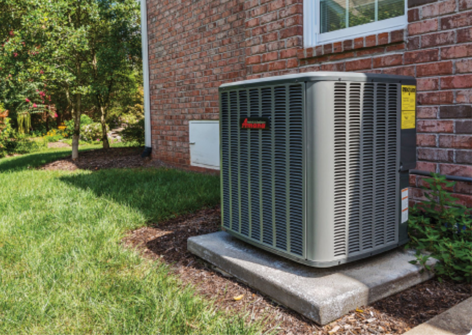 An air conditioner is sitting on the side of a brick house.