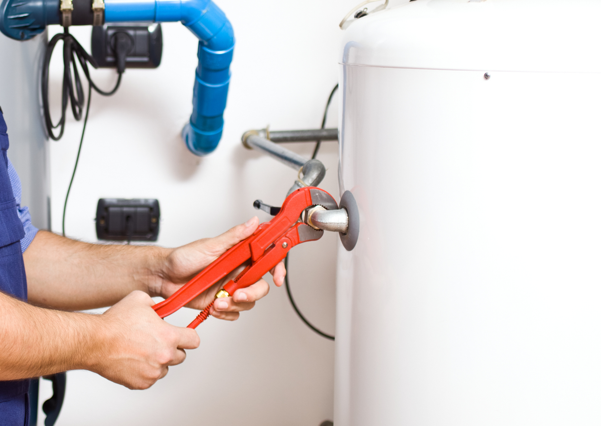 A plumber is fixing a water heater with a wrench.