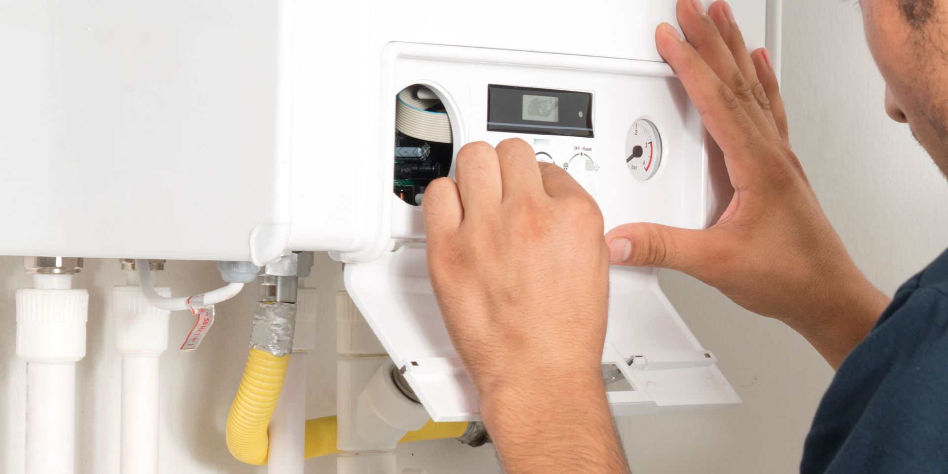 A man is fixing a boiler in a bathroom.