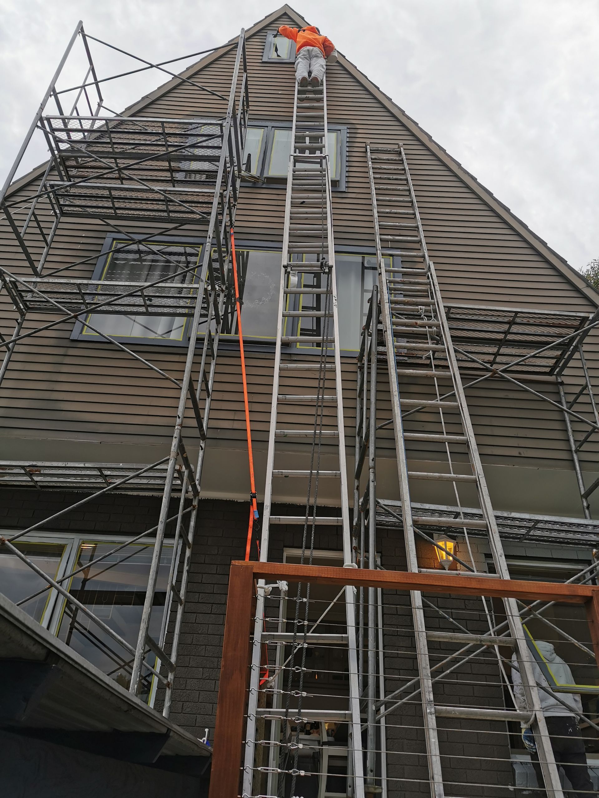 A Man Is Standing On A Ladder In Front Of A Building — Hornsby, NSW — TOG Painting