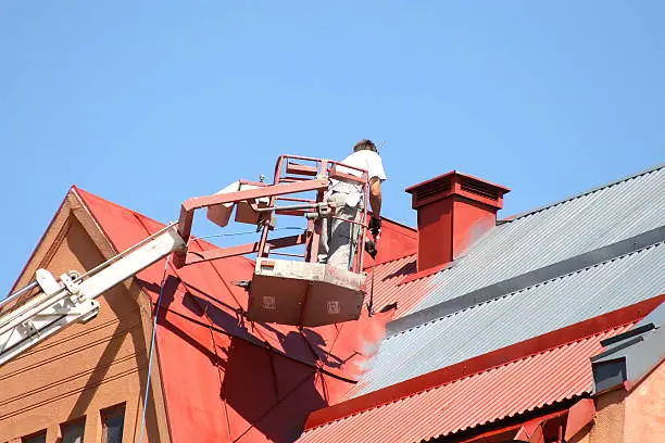 A Man Is Painting The Roof Of A Building With A Crane — Hornsby, NSW — TOG Painting