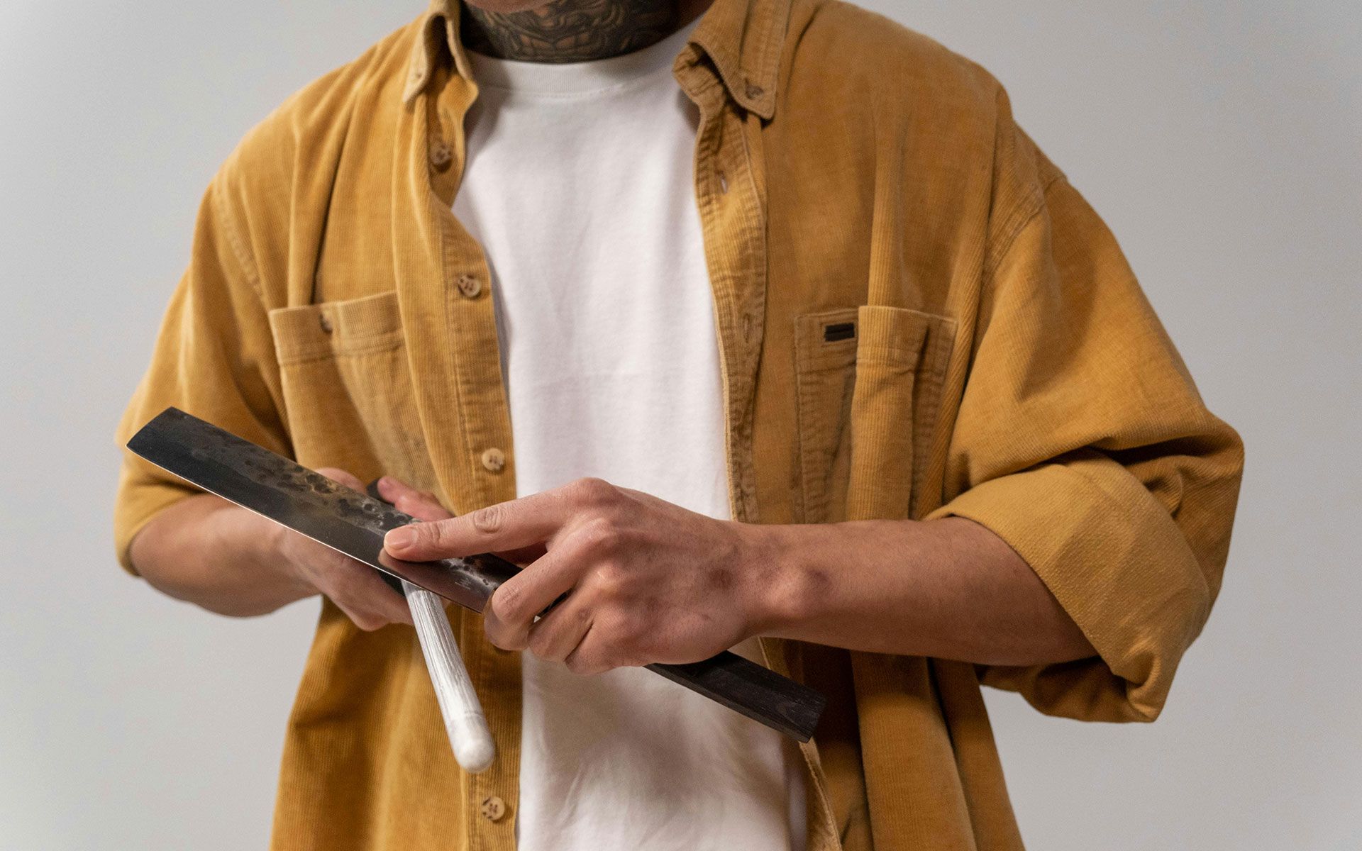 A man in a yellow shirt is holding a saw in his hands.