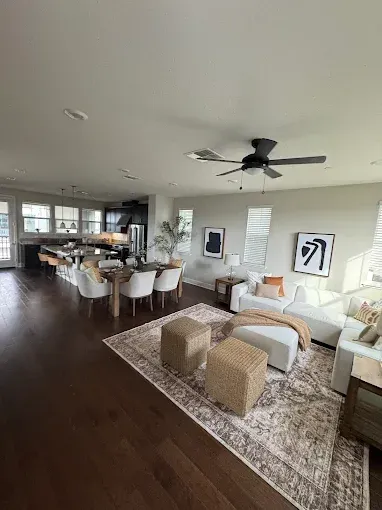 Open-concept living space with a dining area, living room with a white sofa, and a dark wooden floor.
