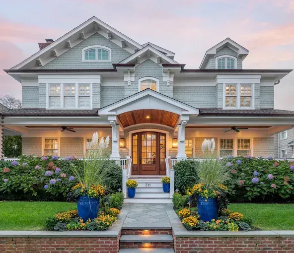 Elegant two-story house with light blue siding, a wooden front door, and a landscaped walkway.