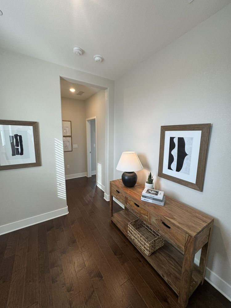 Hallway with a wooden console table, art, and dark wood floors.