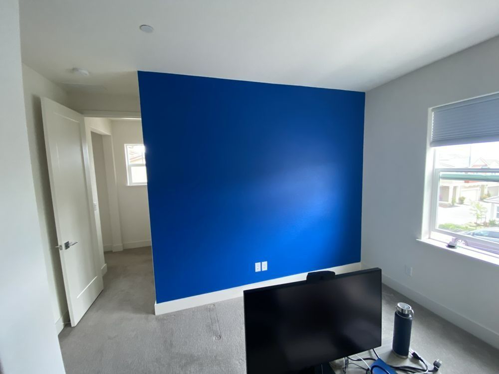 Room with blue accent wall, white walls, carpeted floor, and a computer monitor.