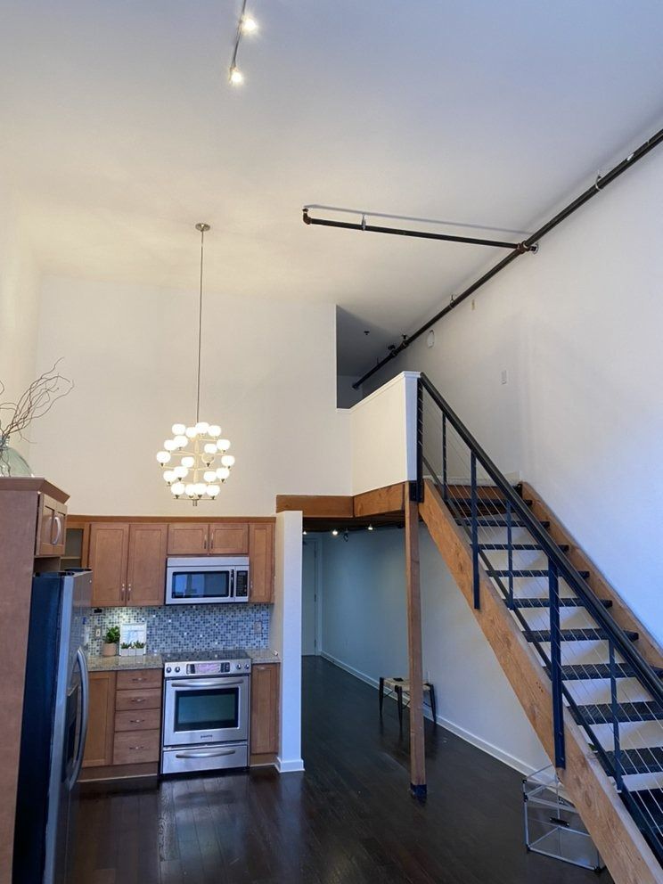 Loft apartment kitchen with high ceilings, stairs to a mezzanine, and a chandelier.