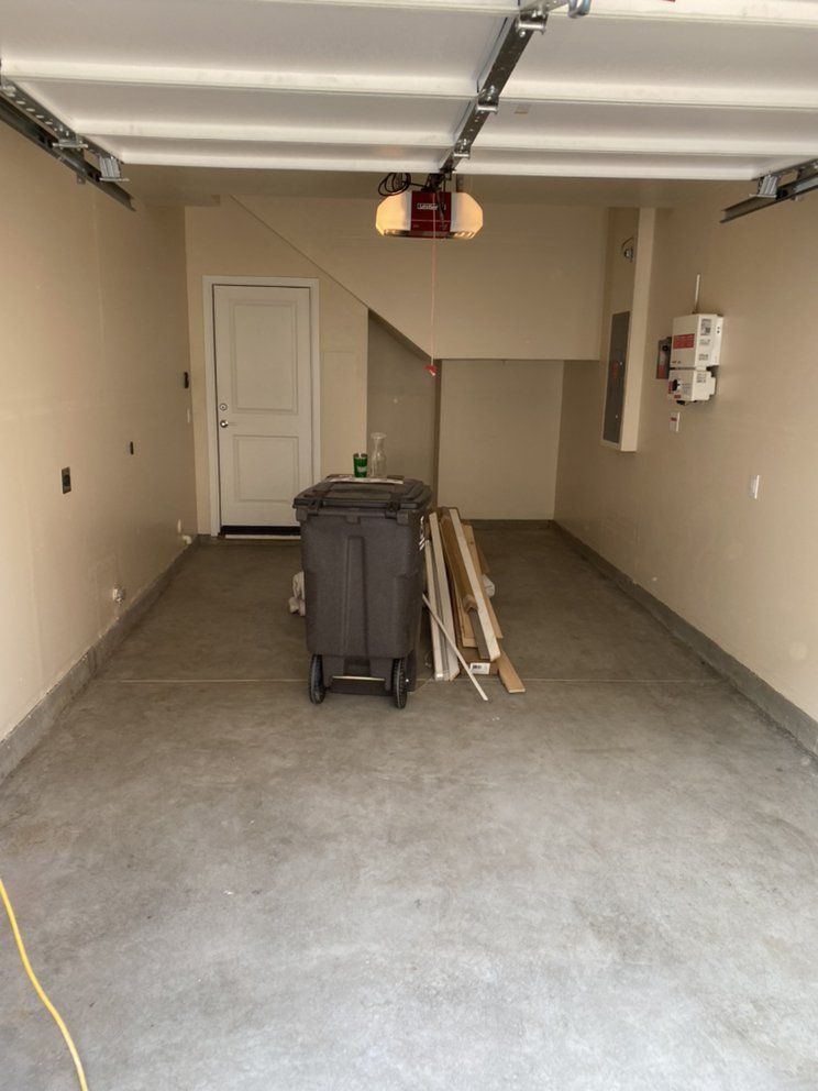 Empty garage with concrete floor, tan walls, and a closed white door.