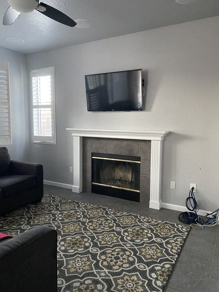 Living room with fireplace, TV above. Dark gray rug, gray walls, white trim.